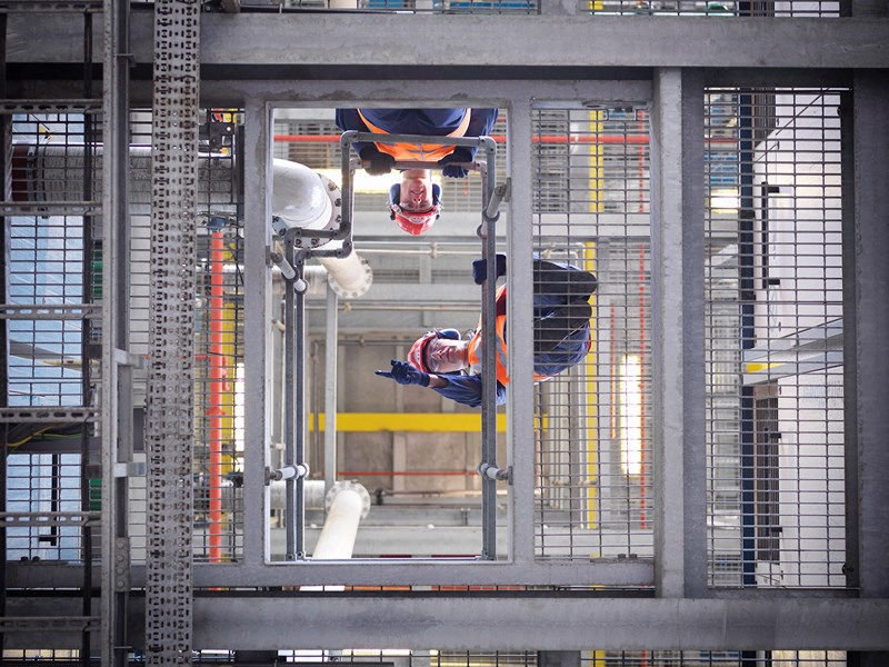 Industrial setting, men on a platform looking down.