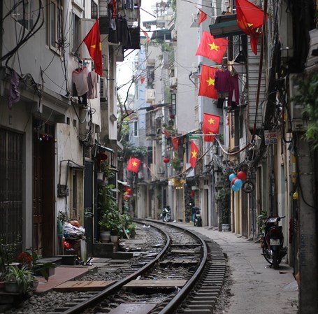 Jernbane i Tiet Hanoi i Vietnam og bygninger med det vietnamesiske flag